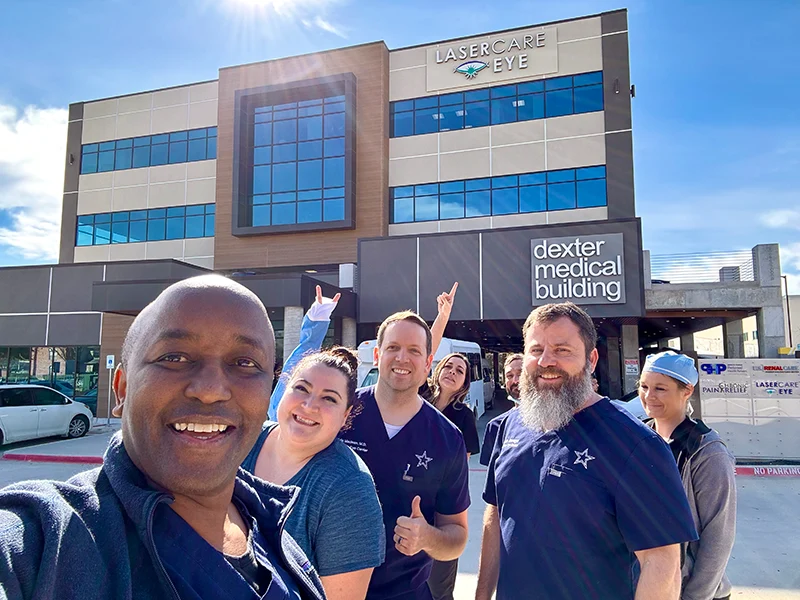 LaserCare Eye team taking a group selfie outside the Dexter Medical Building on a sunny day.
